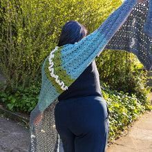 Load image into Gallery viewer, A woman wears a hand-crocheted shawl featuring chevron lace and a row of ruffles down the center back
